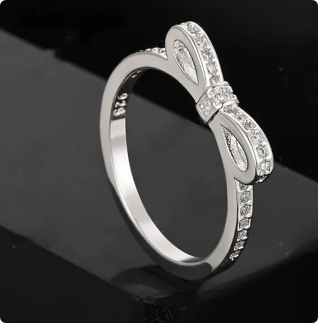 Silver plated bow-shaped ring with clear rhinestone crystal decoration on a model finger