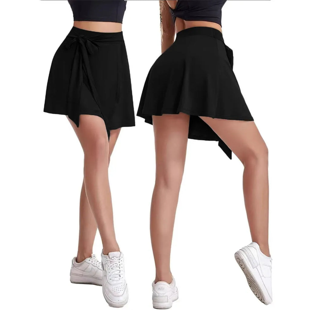 Black thigh-length sports skirt with built-in shorts showing high-waist culotte design and shoulder strap details