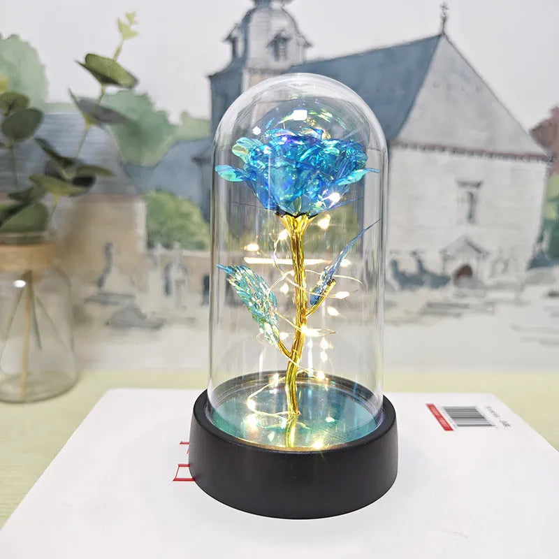 Small glass night lamp with plastic flowers on a black base.