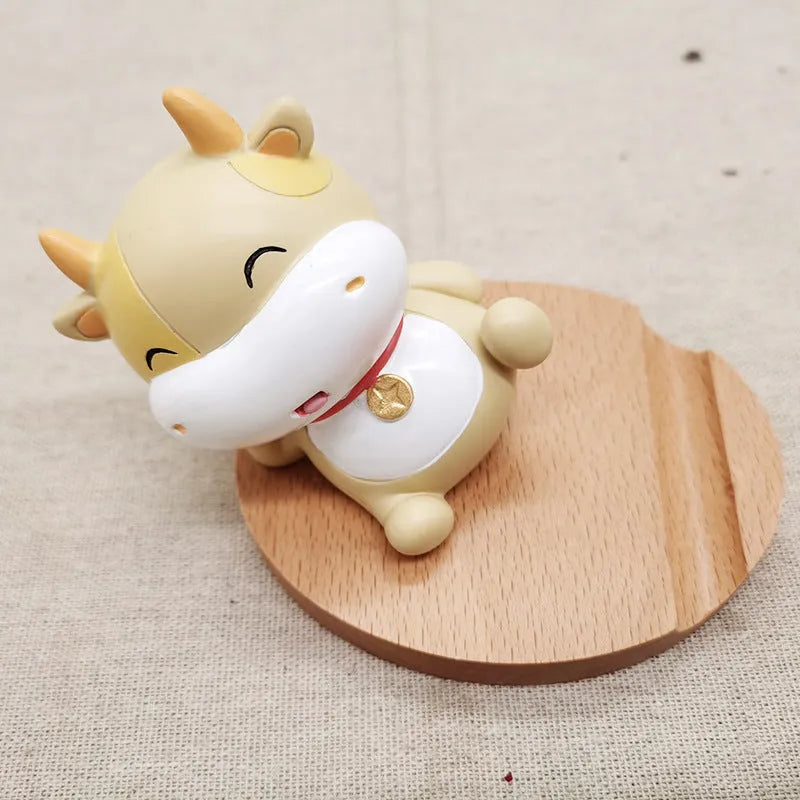 Solid beech wood mobile phone stand with a decorative resin animal ornament and a coin slot.