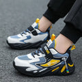 Boys' blue and black platform sports running shoes with Velcro straps on a hard ground surface.