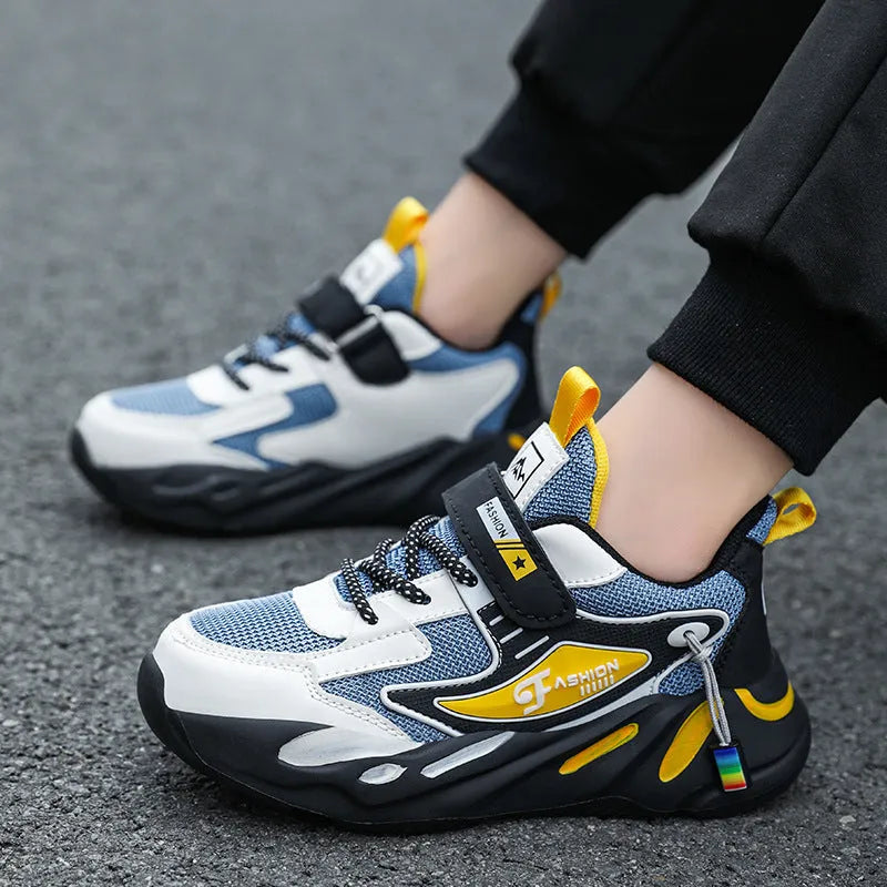 Boys' blue and black platform sports running shoes with Velcro straps on a hard ground surface.