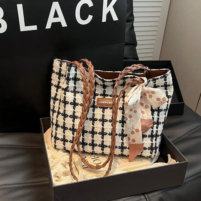 Black woven wool shoulder bag showing horizontal square shape and external pocket.