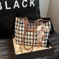 Black woven wool shoulder bag showing horizontal square shape and external pocket.