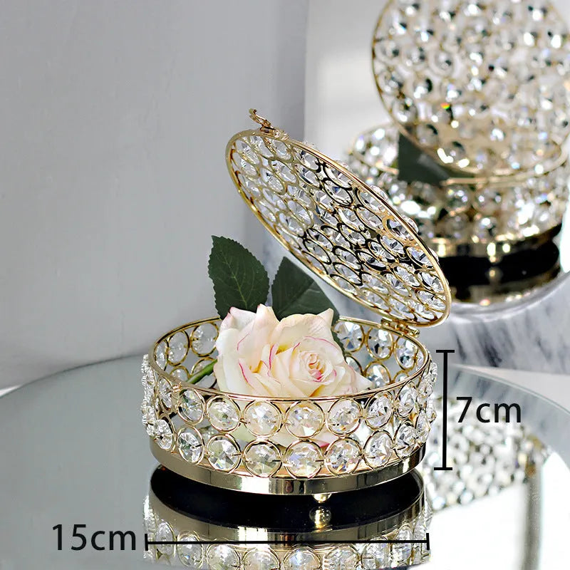 Transparent crystal glass jewelry box with a French gold metal frame on a table.