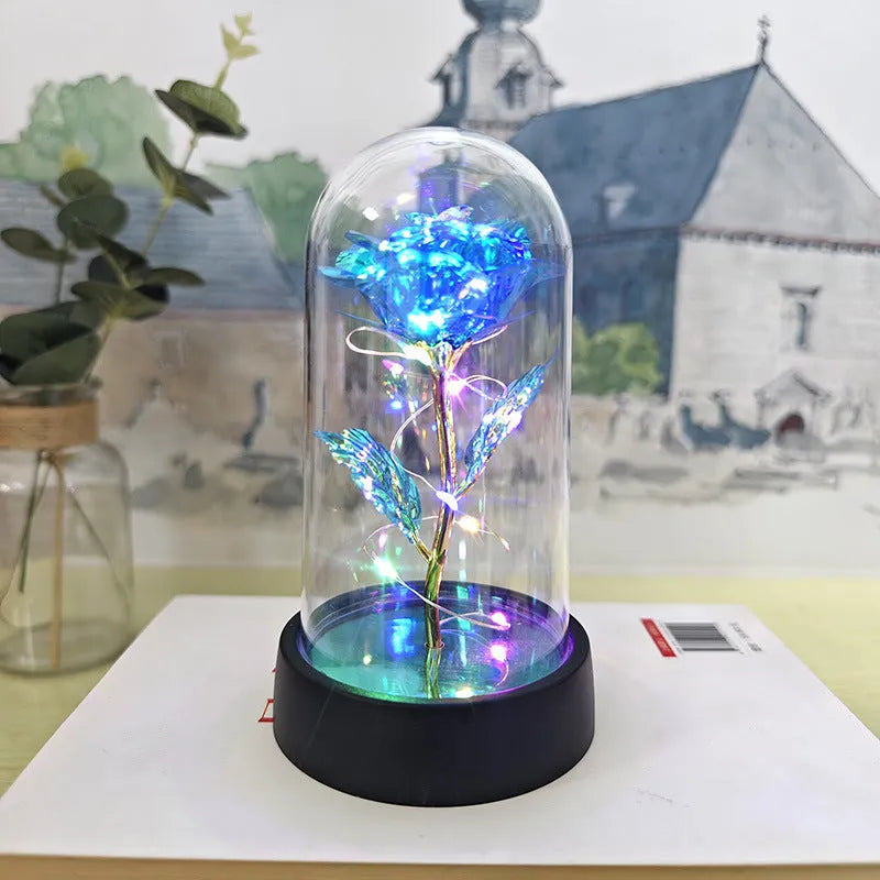 Small glass night lamp with plastic flowers on a black base.