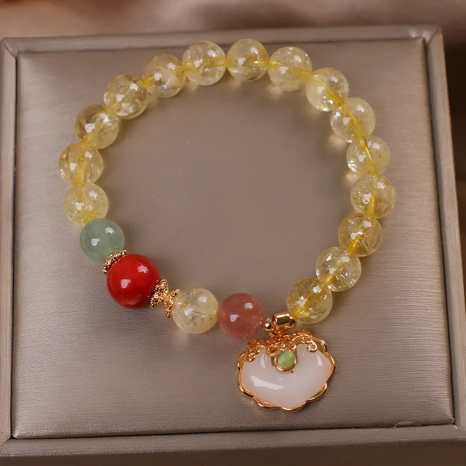 Women's yellow alloy bracelet with a ruyi pendant charm holding natural citrine and yellow hair crystal jade.
