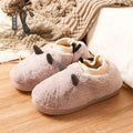 USB electric heating slippers in grey with soft velvet upper and connected USB cable on a wooden floor.