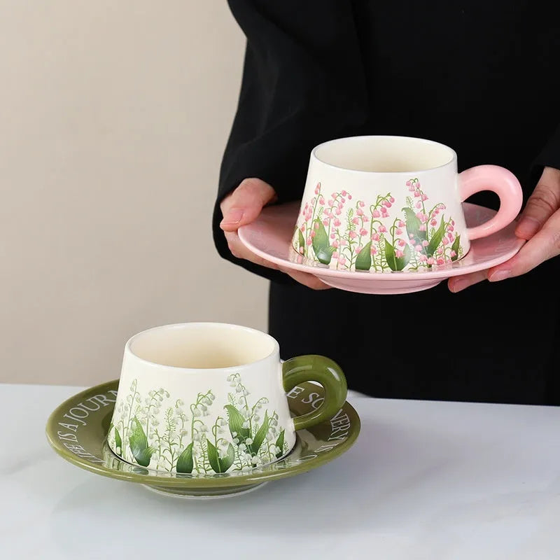 Ceramic coffee cup set with two matching cups, saucers, and stirring spoons featuring hand-painted couple designs