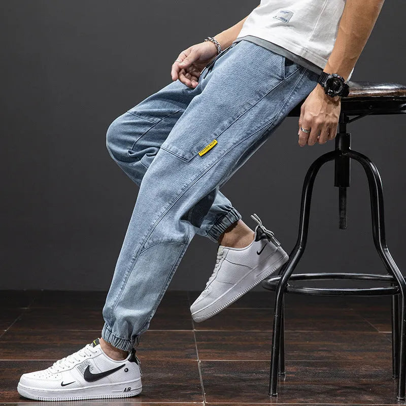 Men's loose-fit cargo jeans in blue, showing straight leg and mid-waist design on a hanger.
