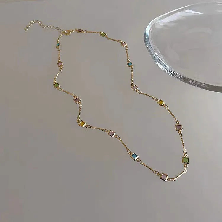 Square colour geometric clavicle chain necklace with artificial crystal details in gold tone.