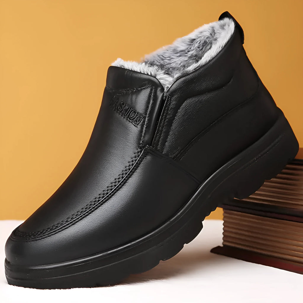 Men's black fleece-lined slip-on winter shoes with a rubber sole on a grey background.