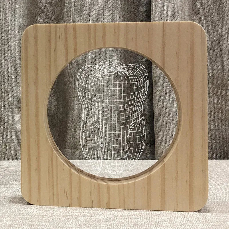 Wood-coloured tooth-shaped acrylic night lamp with USB cable on a surface.