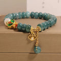 Close-up of a women's bracelet with blue jade and white agate abacus beads, butterfly charms, and rhinestones on an alloy chain.