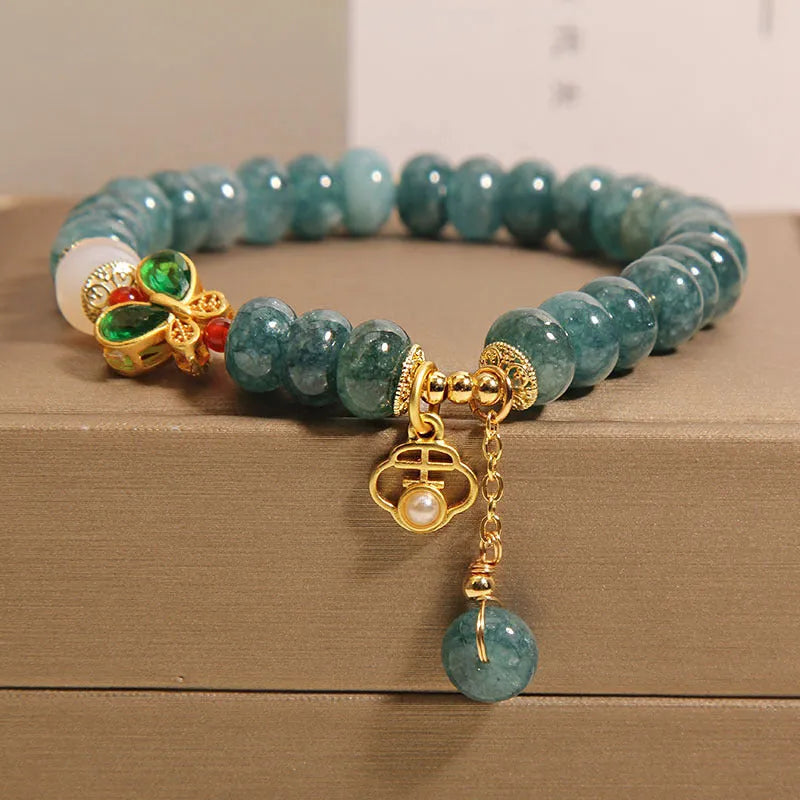 Close-up of a women's bracelet with blue jade and white agate abacus beads, butterfly charms, and rhinestones on an alloy chain.