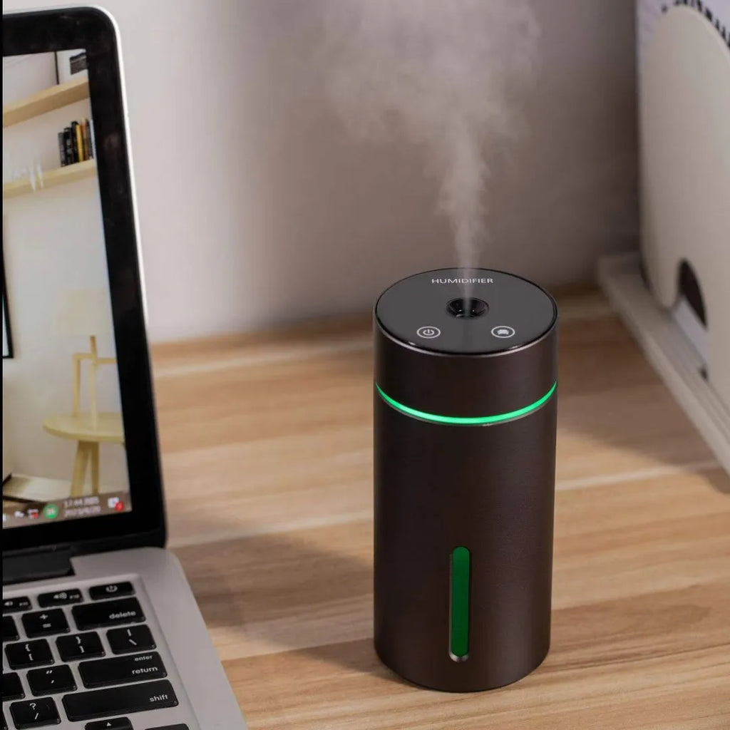 Black aluminium car humidifier and essential oil diffuser with night light on a desk.