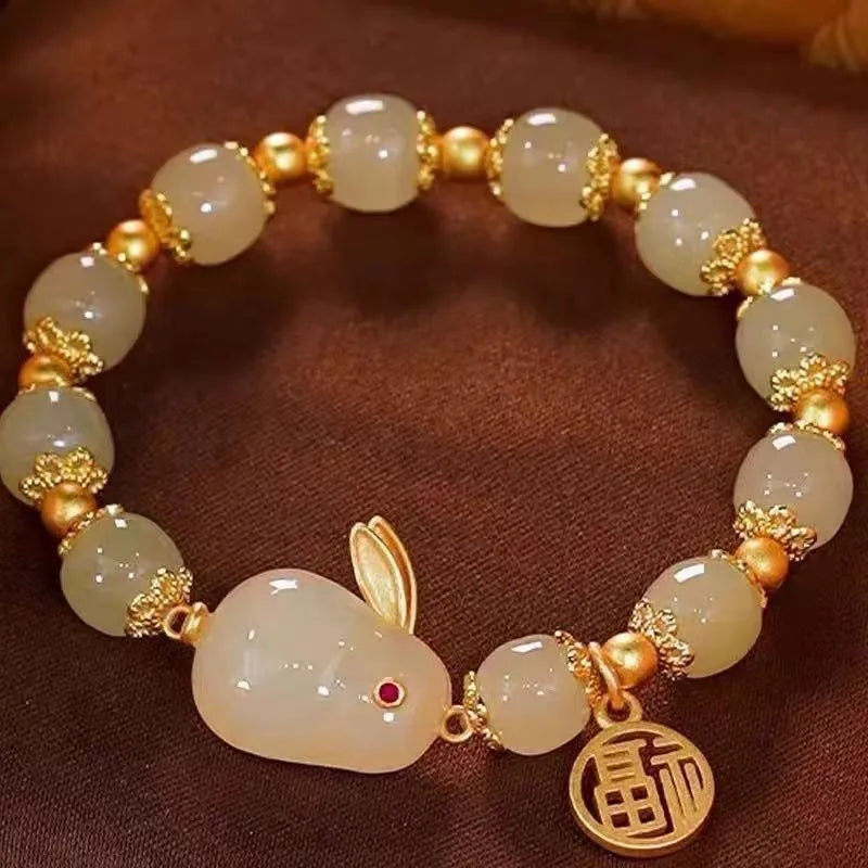 Women's black bracelet with a green jade hare charm, fu character symbol and lily motif design.