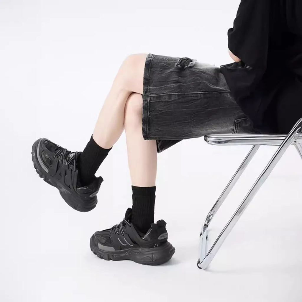 Man wearing black washed ripped denim shorts in a loose, retro style