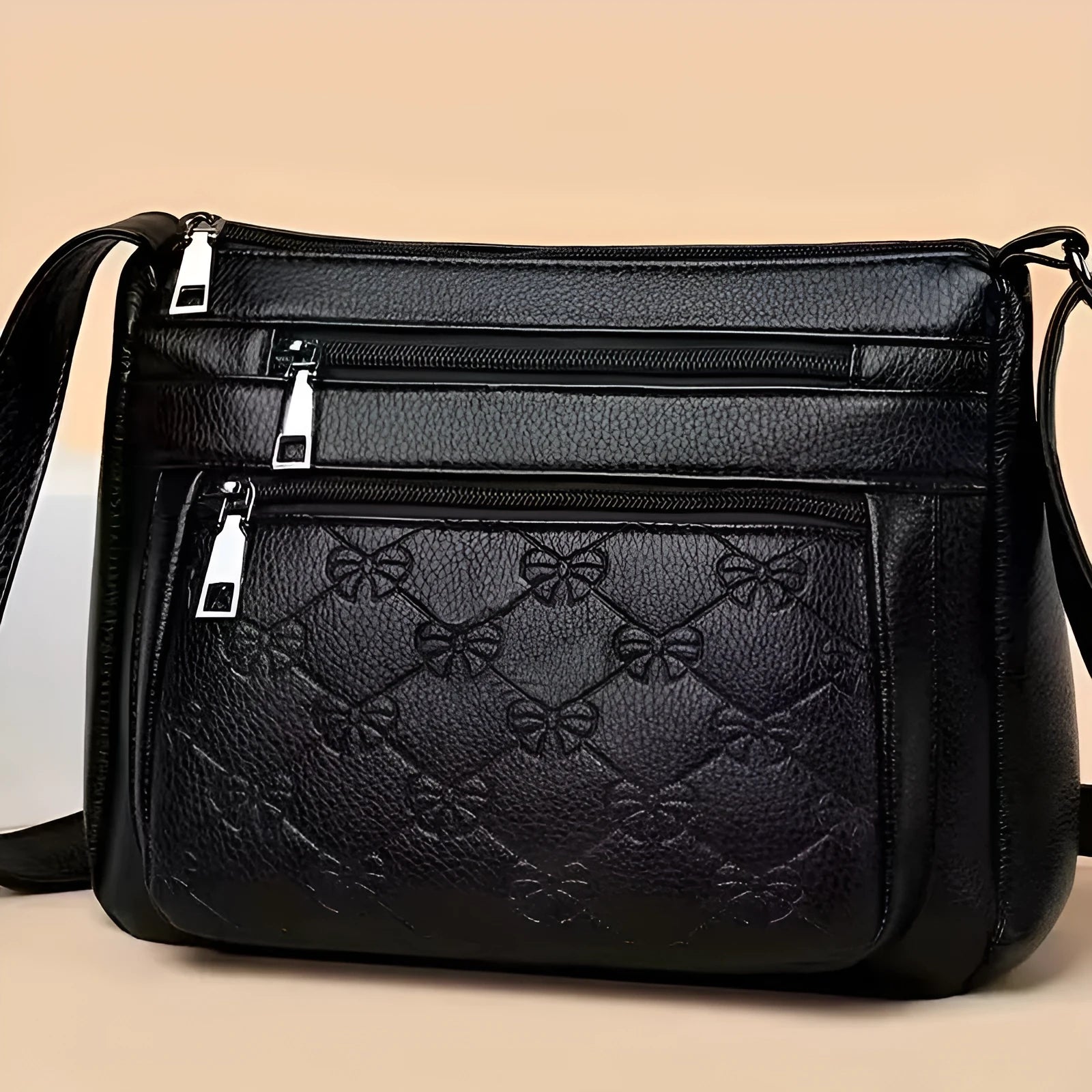 Black women's crossbody bag with embossed butterfly pattern showing phone pocket and external slit