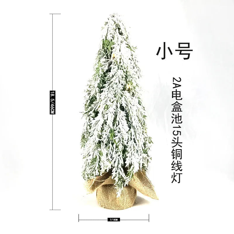 24-inch artificial Christmas tree with snow spray finish and integrated lights on desktop