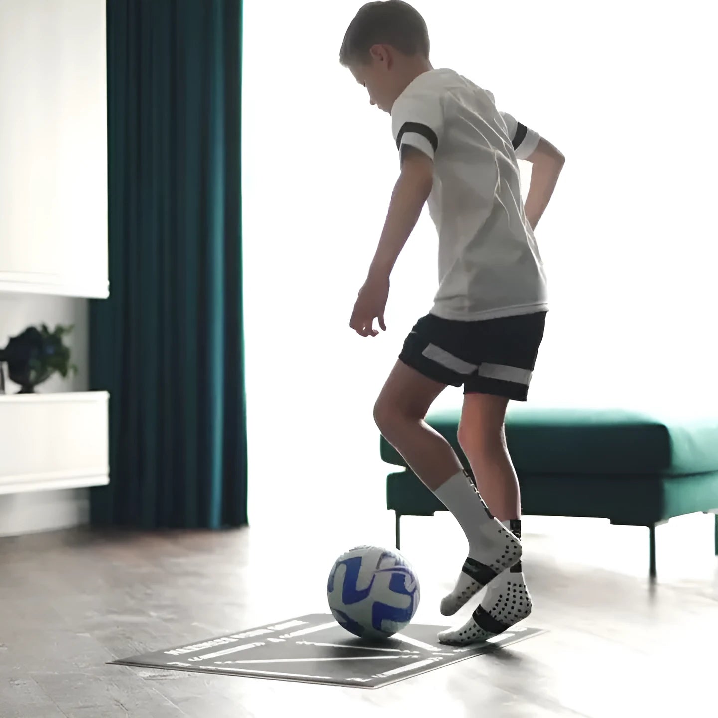Black football training mat on a flat surface, dimensions 60cm by 90cm.