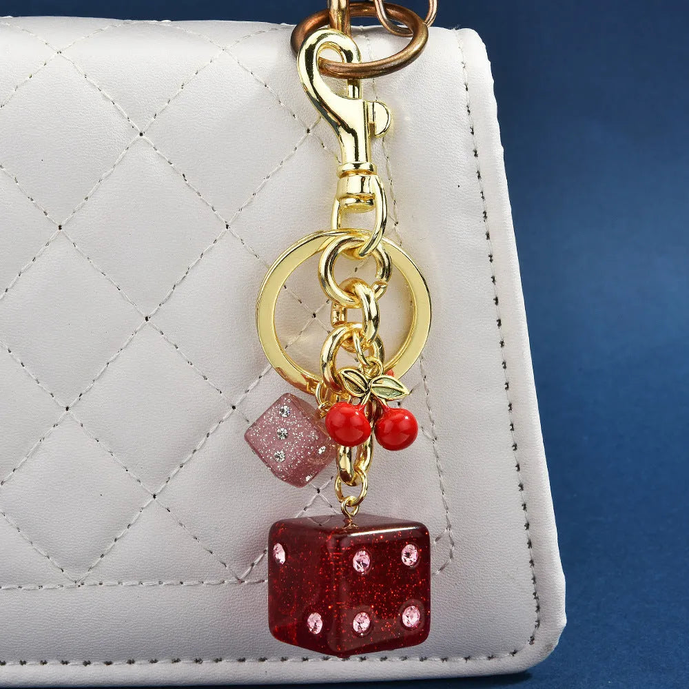 Square metal keychain pendant with a vintage cherry red and white dice design.