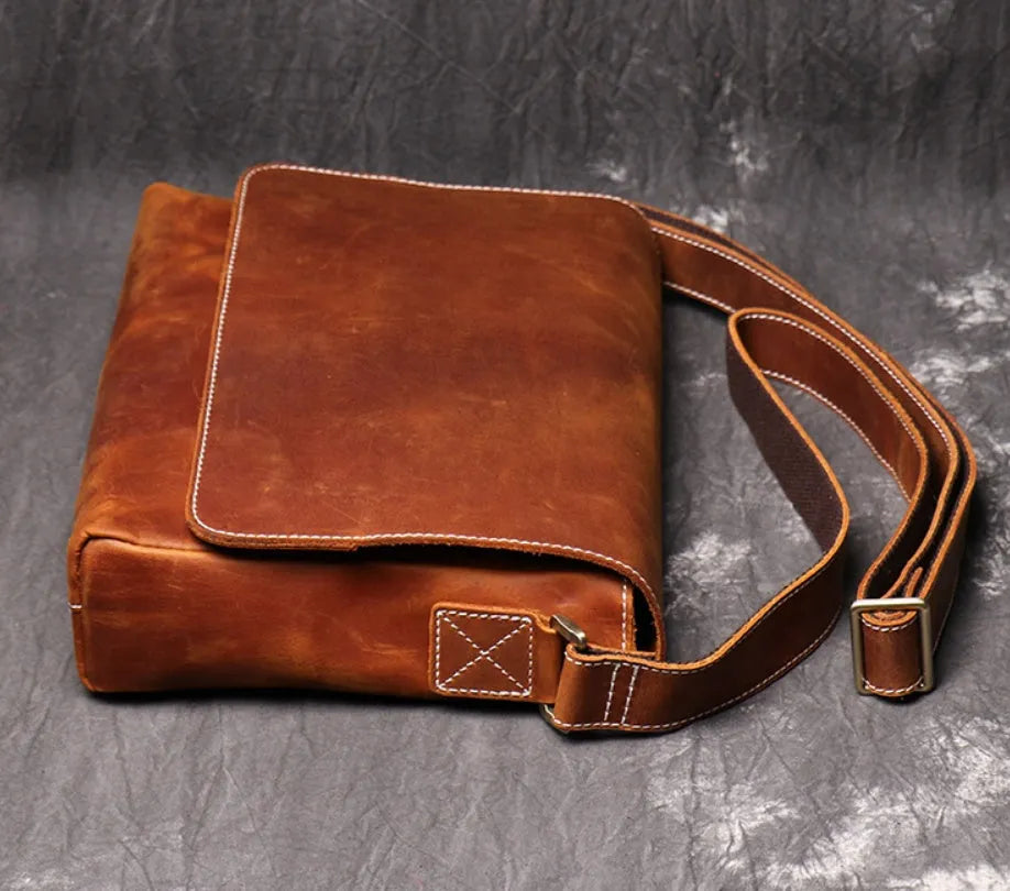 Vintage brown leather men's messenger bag with shoulder strap showing internal organiser pockets.
