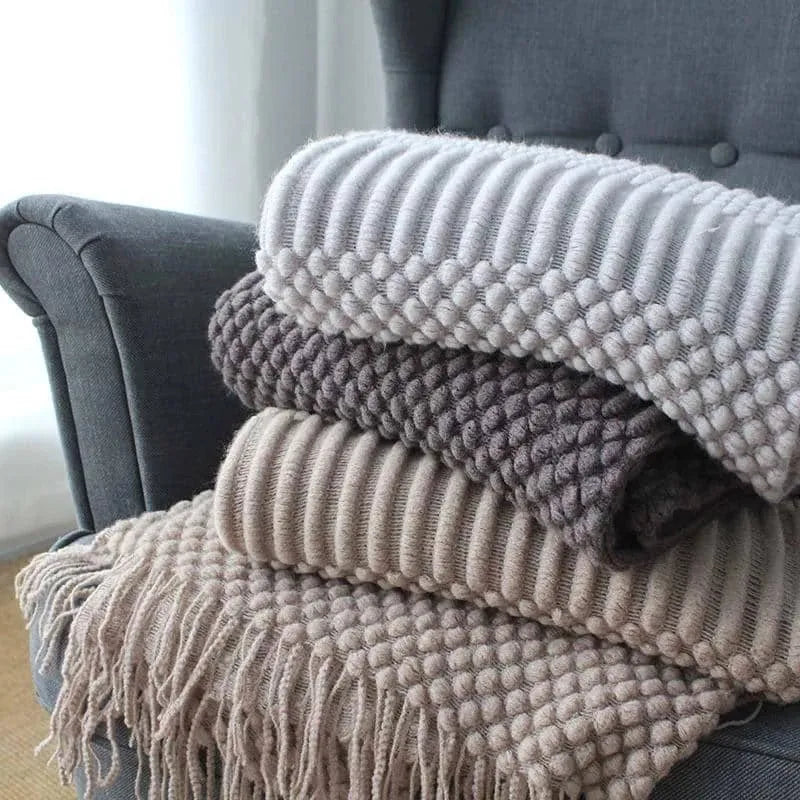Small light grey polyester blanket folded on a sofa