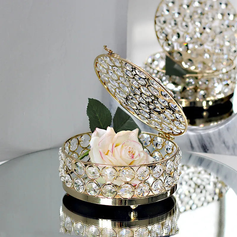 Transparent crystal glass jewelry box with a French gold metal frame on a table.
