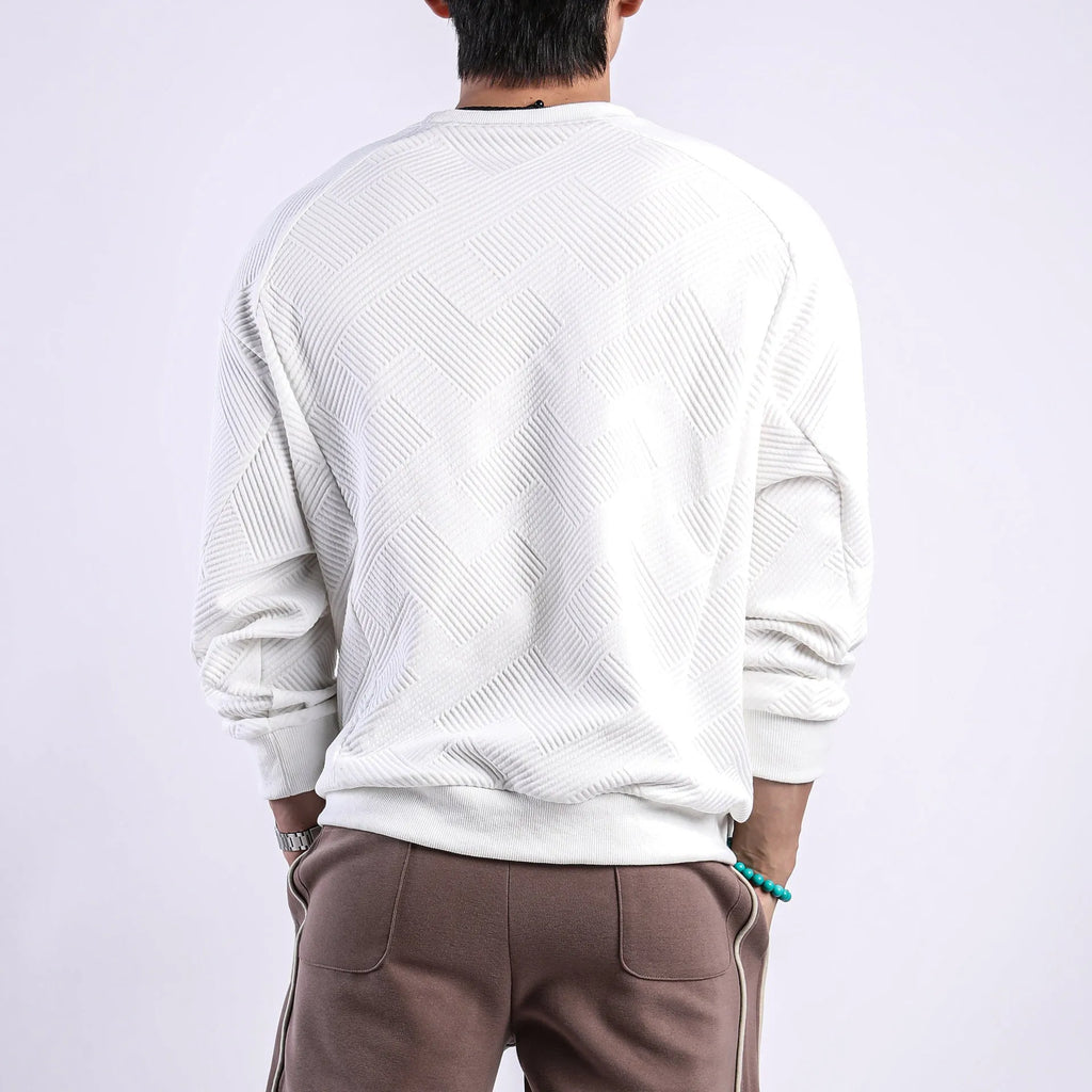 Man wearing a loose-fitting, long-sleeved army green pullover sweater with a textured twill jacquard pattern.
