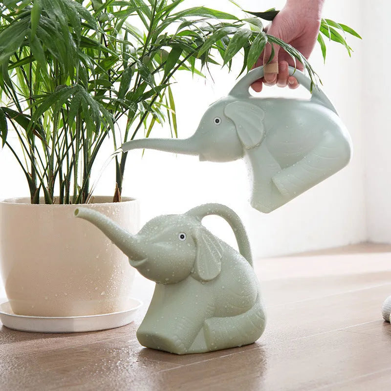 Pink baby elephant-shaped watering can with a long spout and baby bottle handle on a table.