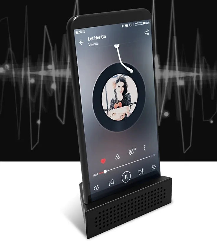 Pink portable ABS mobile phone amplifier bracket holding a smartphone horizontally on a desk.