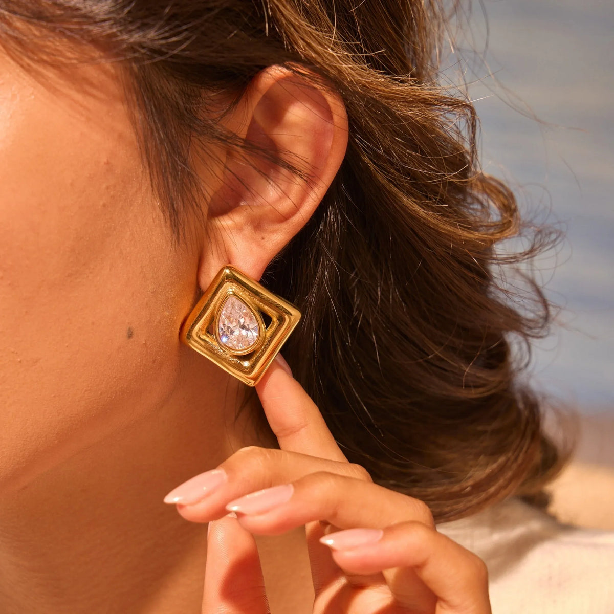 Gold coloured geometric stud earrings with an inlaid water drop zircon stone.