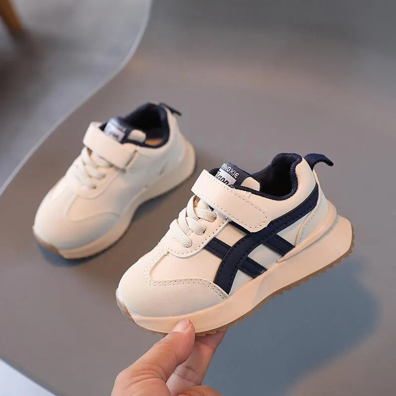 Children's white synthetic leather sneakers with Velcro strap and rubber sole.