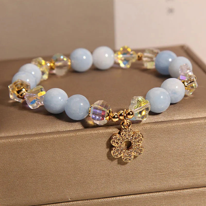 Women's aquamarine crystal bracelet with a four-leaf clover charm and pearl decorative elements.