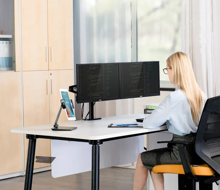 Silver foldable aluminium phone and tablet holder on a desk, showing 360-degree rotation feature.