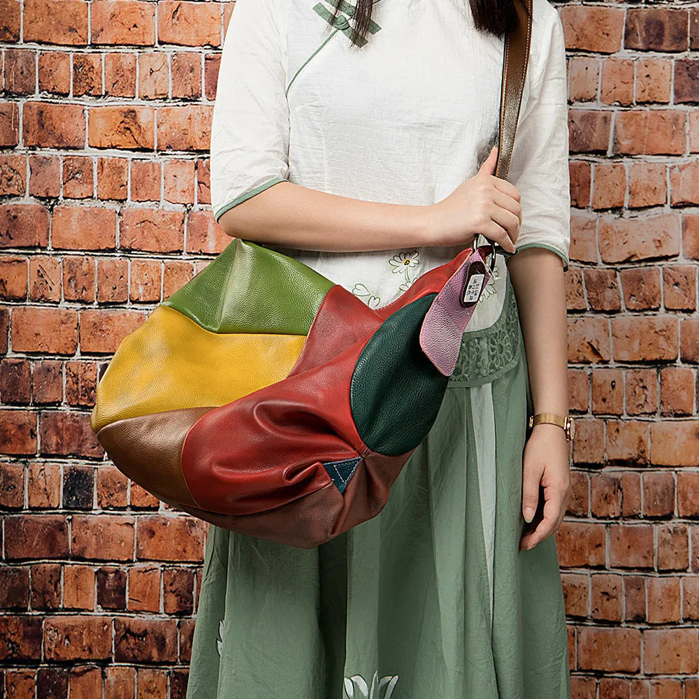 Brown cowhide leather crossbody shoulder travel bag with stitching detail, shown with a laptop and magazine inside.
