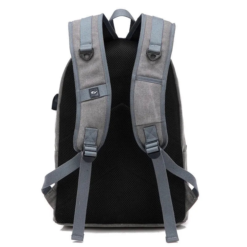 Canvas backpack in grey colour showing USB charging port, front zipper pocket, and adjustable shoulder straps