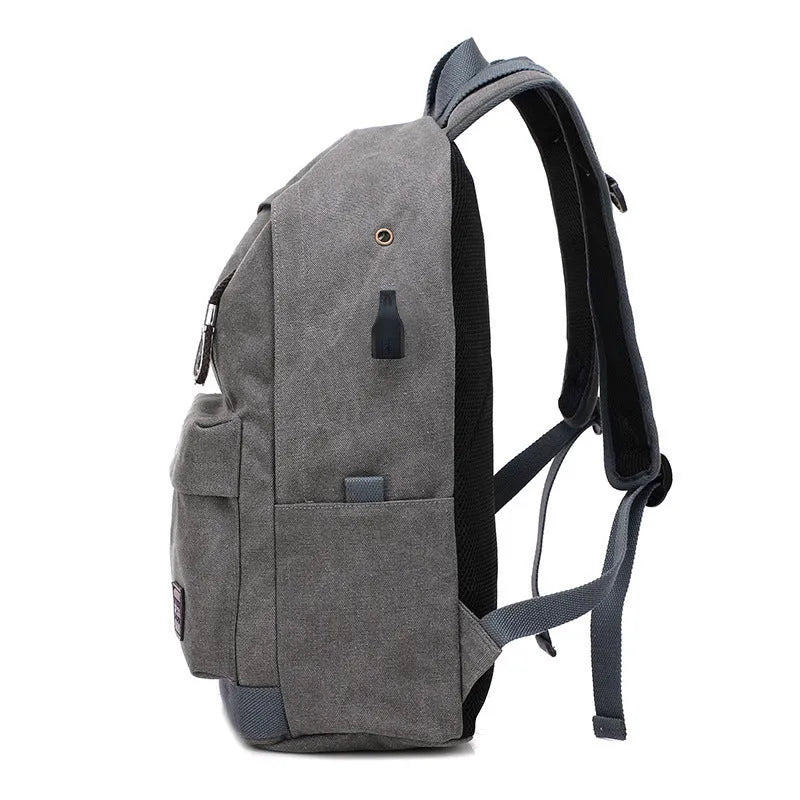 Canvas backpack in grey colour showing USB charging port, front zipper pocket, and adjustable shoulder straps