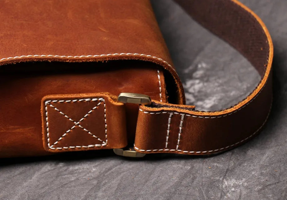 Vintage brown leather men's messenger bag with shoulder strap showing internal organiser pockets.