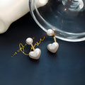 Close-up of a women's heart-shaped alloy stud earring with electroplated finish and central gemstone inlay.