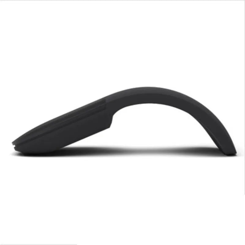 A closed black folding Bluetooth wireless mouse showing its compact size next to a laptop.