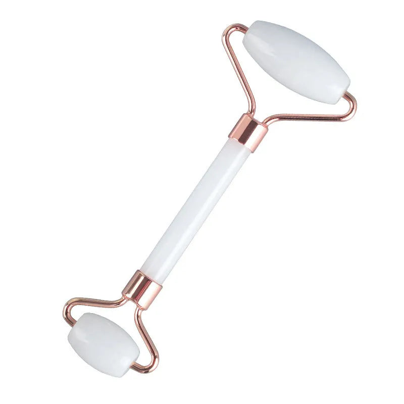 White jade double-headed facial roller and gua sha scraping board set on a plain background.