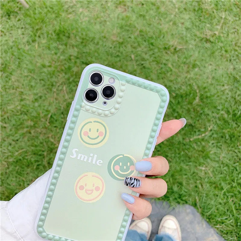 Green iPhone case with geometric smiley face design and polka dot frame on a TPU back cover.