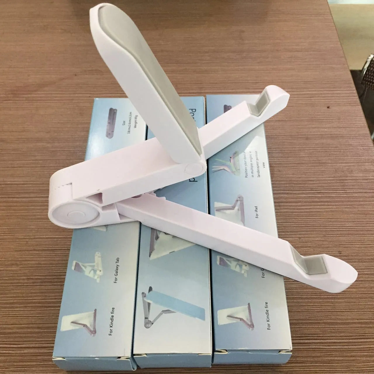 Black foldable tablet holder displaying smartphone at adjustable angle on desk