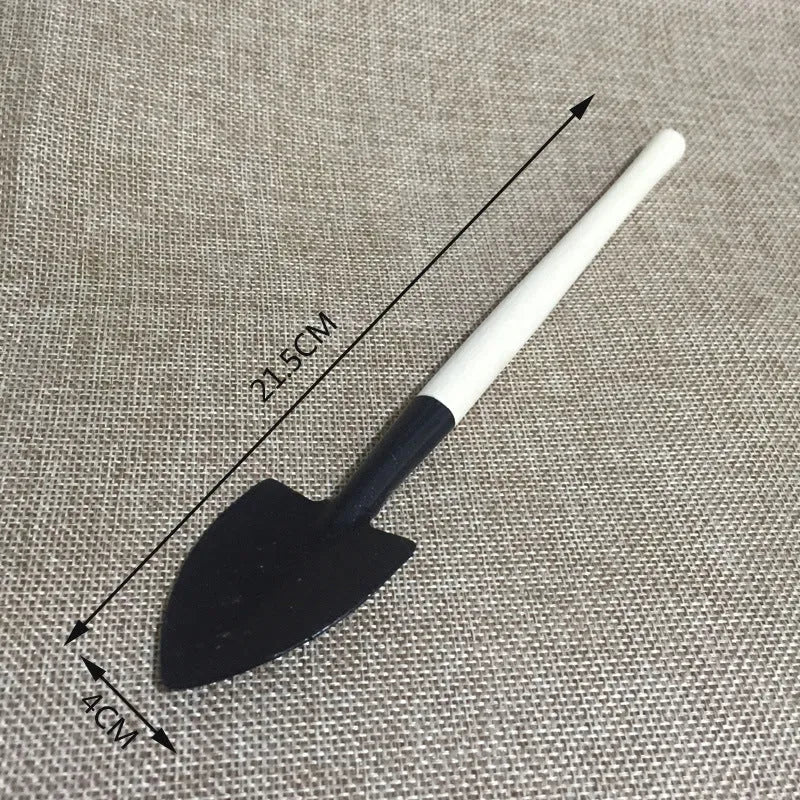 Succulent gardening tool set showing mini shovel, watering can, tweezers, brush, and rake on a table