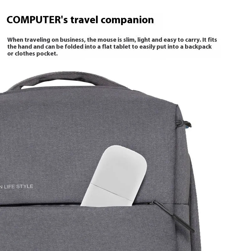 A closed black folding Bluetooth wireless mouse showing its compact size next to a laptop.