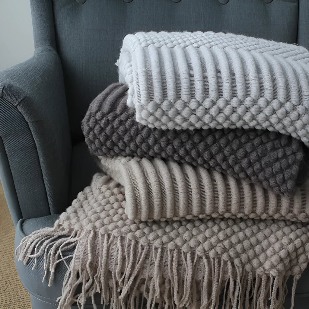 Small light grey polyester blanket folded on a sofa