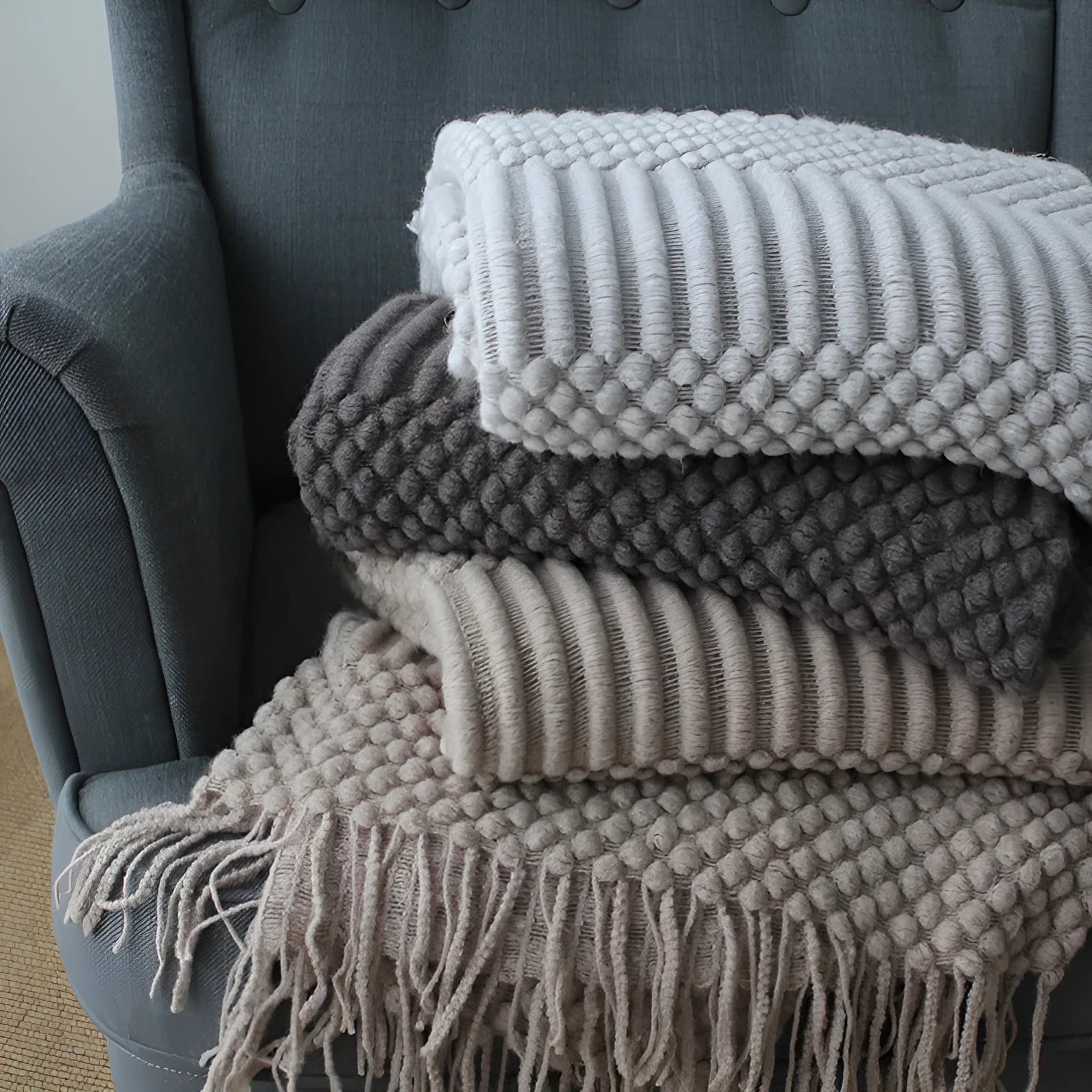 Small light grey polyester blanket folded on a sofa