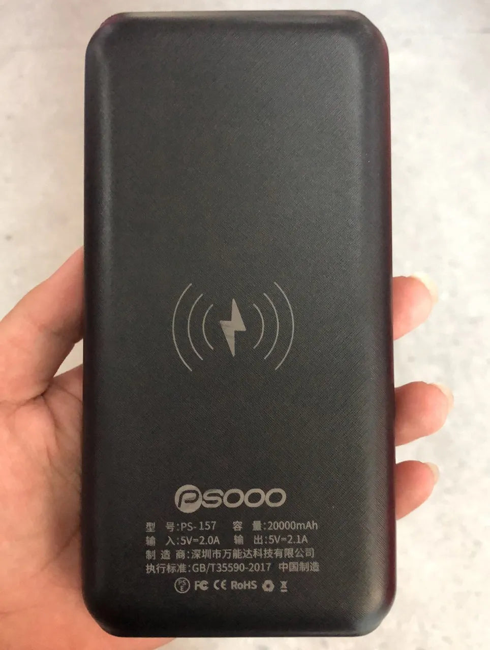 Black solar power bank with wireless charging pad, three USB ports, and an LED flashlight.